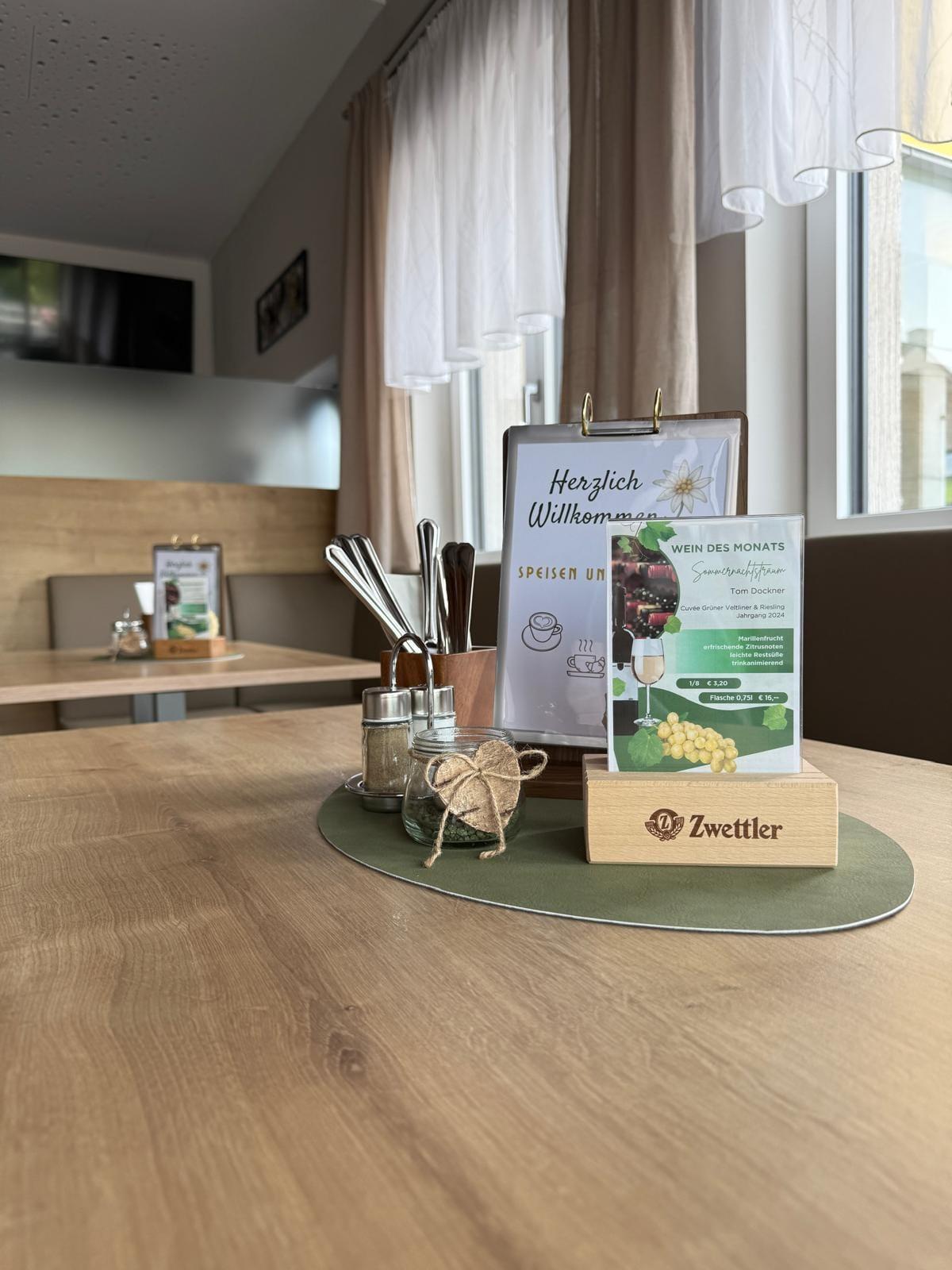 Gedeckter Tisch mit Speisekarte und Wein des Monats